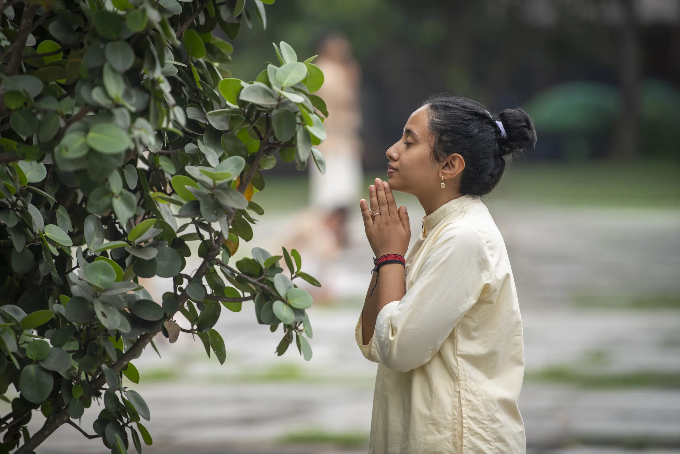 Yoga practitioner in namaskar posture beside greenery